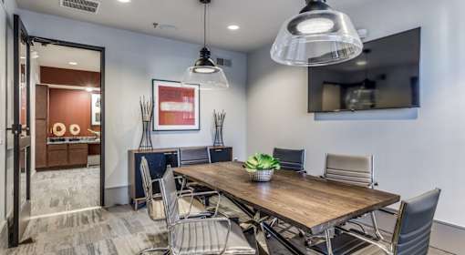A modern dining room with a wooden table and grey chairs.