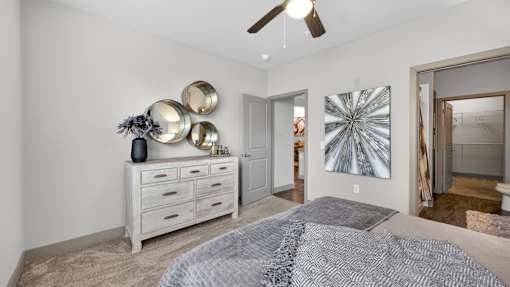 A bedroom with a bed, dresser, and ceiling fan.