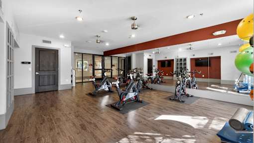 A gym with exercise equipment and a mirrored wall.