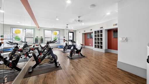 A gym with exercise bikes and a mirror on the wall.