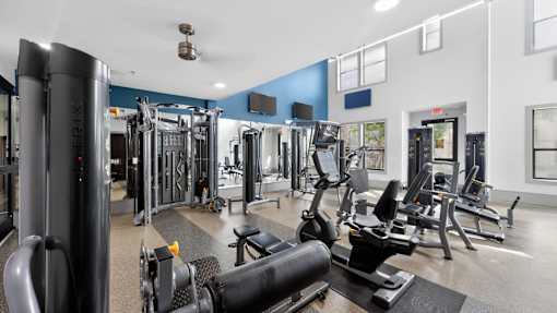 A gym with a variety of equipment including a squat rack, a leg press machine, and a bench press.