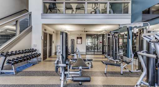A spacious gym with a variety of equipment and a staircase.
