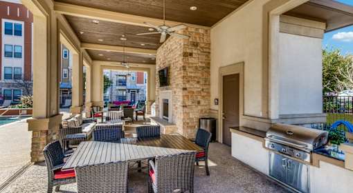 A patio with a table and chairs and a grill.