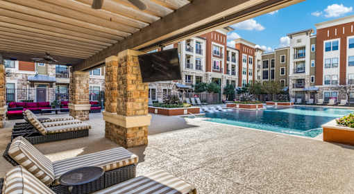 A pool area with sun loungers and a building in the background.