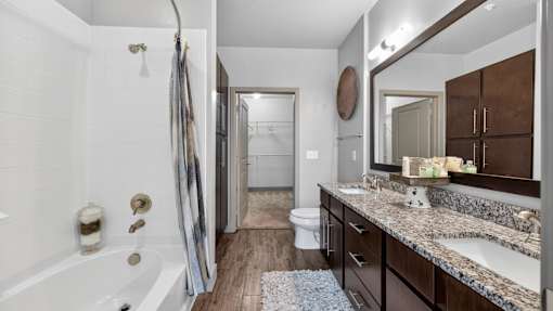 A bathroom with a white tub and a wooden floor.