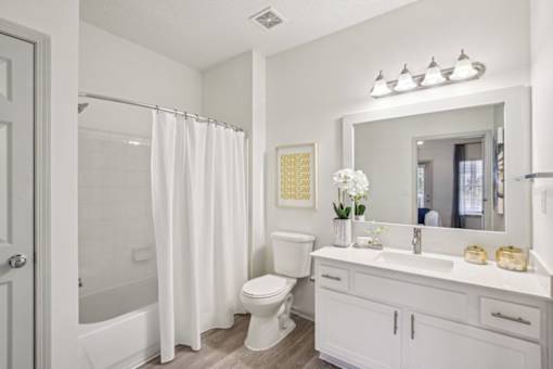 A white bathroom with a toilet, sink, and shower.