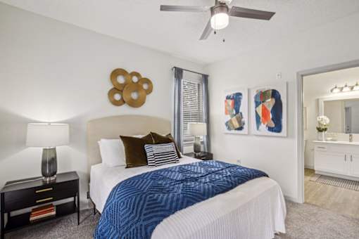 A bedroom with a bed, nightstand, and artwork on the wall.