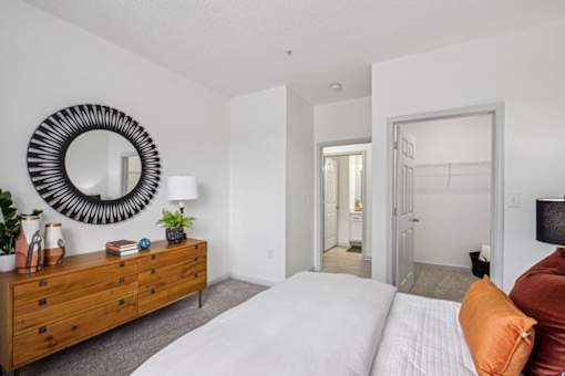 A bedroom with a white bed and a wooden dresser.