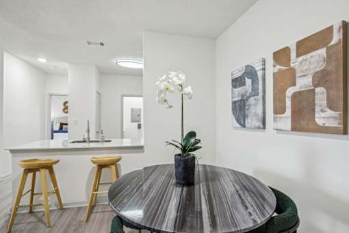 A modern kitchen with a bar area and a dining table with a plant on it.