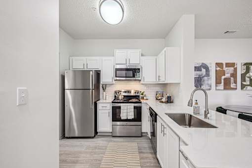 A modern kitchen with white cabinets and stainless steel appliances.