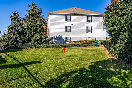 A white house with a red fire hydrant in front of a green lawn.
