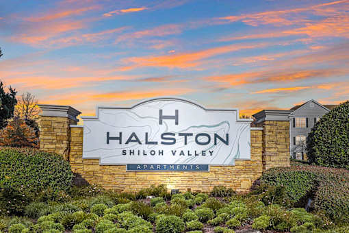 The Halston Shiloh Valley Apartments sign is displayed in front of a beautiful sunset.