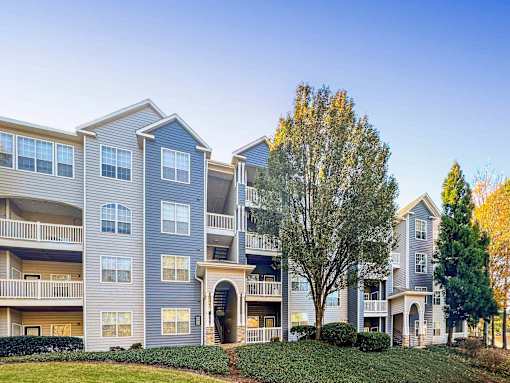 A large apartment complex with multiple balconies and a green lawn in front.