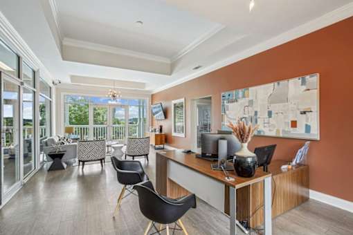 A room with a desk and chairs with a painting on the wall.