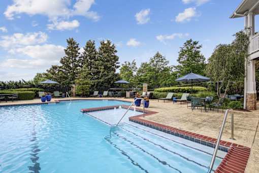 A swimming pool with a red brick border and a diving board.