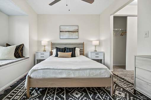 A bedroom with a large bed, two nightstands, and a ceiling fan.