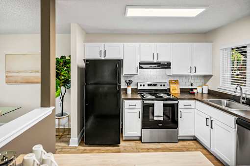 A modern kitchen with white cabinets and black appliances.