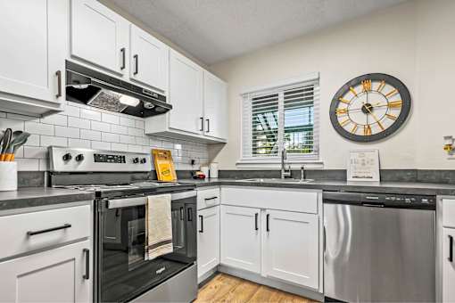 A modern kitchen with white cabinets and black appliances.