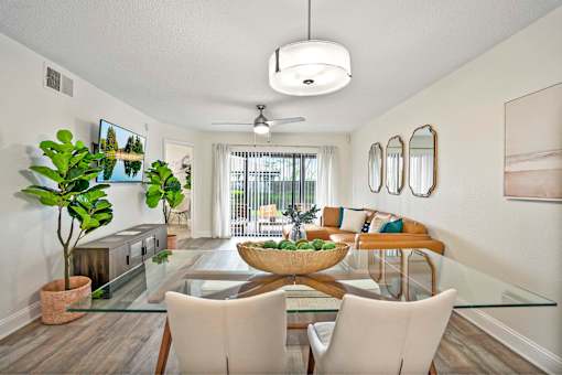 A modern dining room with a glass table and white chairs.