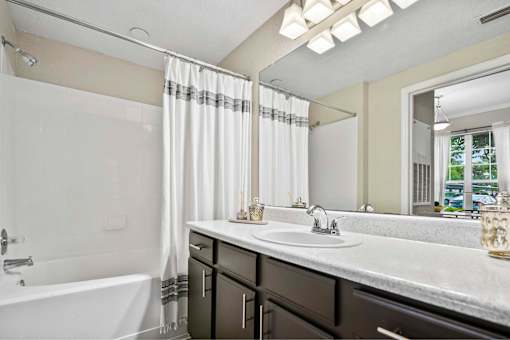 A bathroom with a white tub, sink, and a mirror.