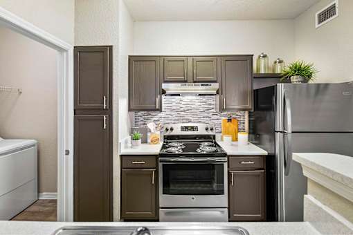 A kitchen with a stove top oven and a refrigerator.