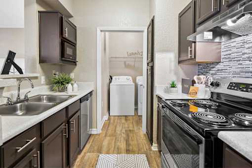 A modern kitchen with dark brown cabinets and a white dishwasher.