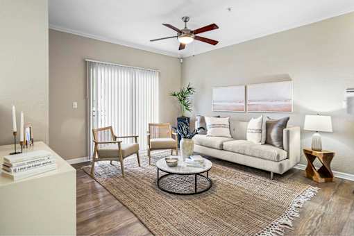 A living room with a white couch, a coffee table, and a ceiling fan.