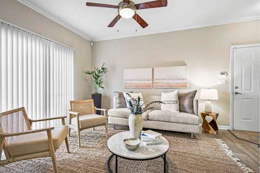 A living room with a white couch, a coffee table, and a ceiling fan.