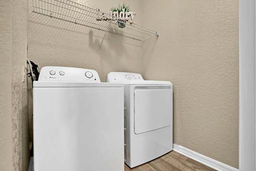 Two white front loading washing machines in a laundry room.