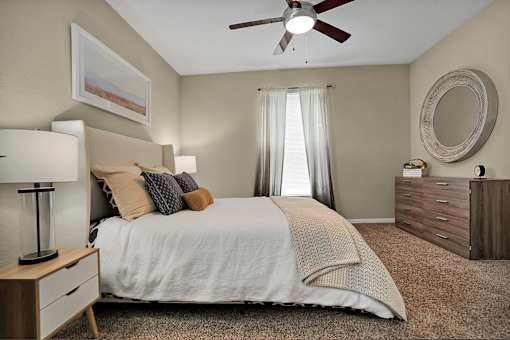 A bedroom with a bed, nightstand, and a ceiling fan.