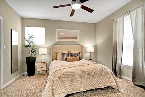A bedroom with a large bed and a ceiling fan.