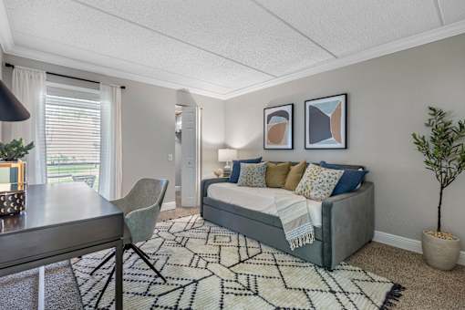 A bedroom with a bed, a chair, and a rug.