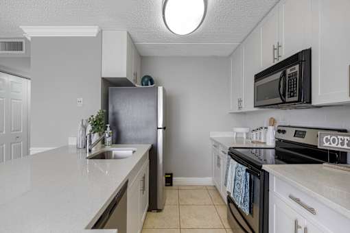 A kitchen with a refrigerator, microwave, and oven.