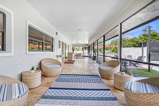 A long white covered walkway with wicker chairs and tables on either side.