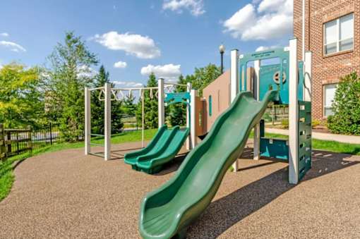 A playground with a green slide and a climbing frame.