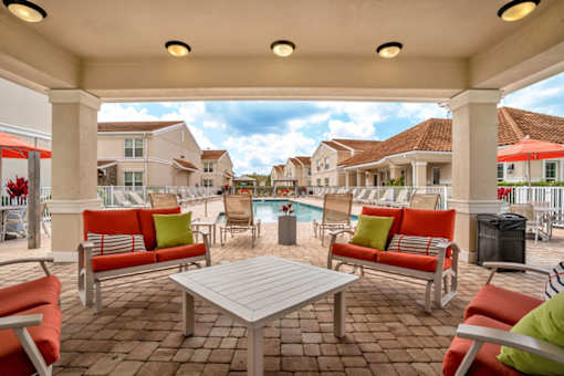 A pool surrounded by chairs and a fence.