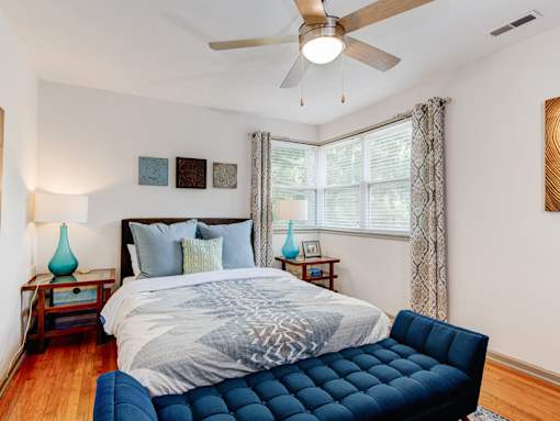 A bedroom with a bed, a ceiling fan, and a blue chair.