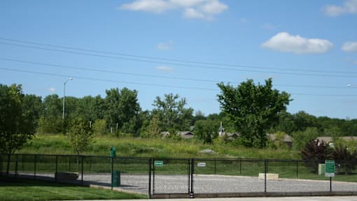 A fenced area with a sign and trees in the background.