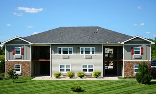A large house with a grey roof and a green lawn in front.