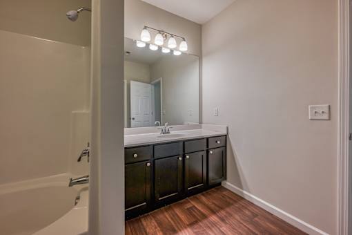 A bathroom with a white tub and a large mirror.