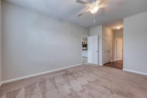 A room with a ceiling fan and carpeted floor.