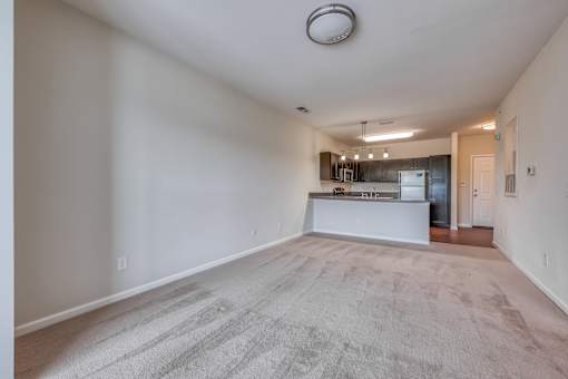 A spacious living room with a kitchen in the background.