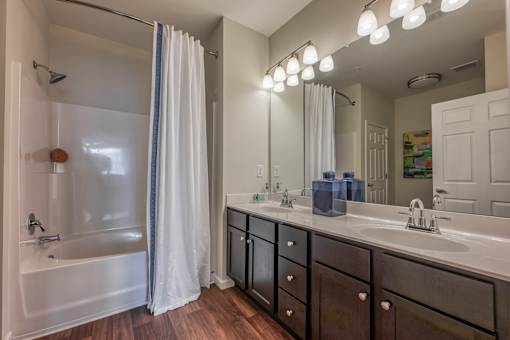A bathroom with a white tub, sink, and shower curtain.