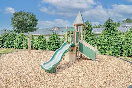 A playground with a green slide and a wooden structure.