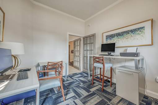 A room with a desk, chair, and a framed picture on the wall.