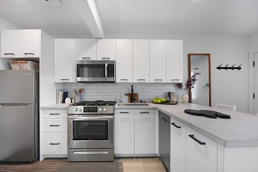 A modern kitchen with white cabinets and stainless steel appliances.