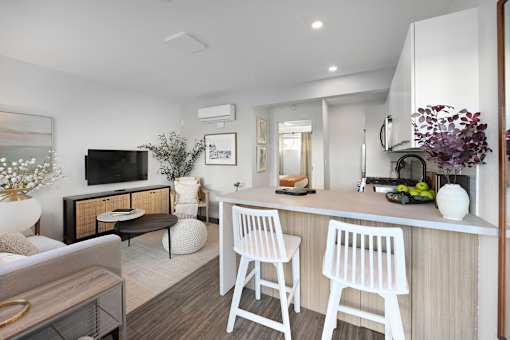 A modern kitchen with white chairs and a wooden counter.