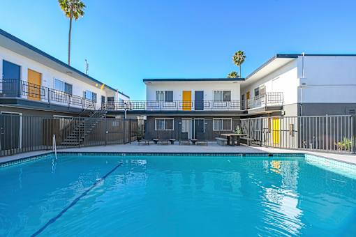 A pool in front of a building with a palm tree in the background.