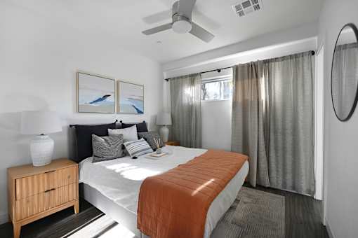 A bedroom with a bed, nightstand, and a painting on the wall.