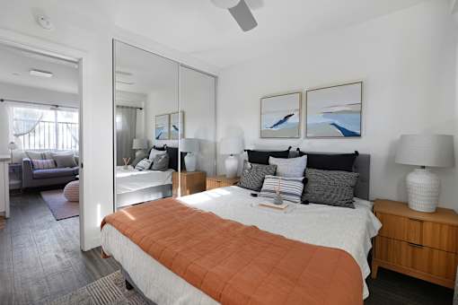 A bedroom with a large bed and a mirror on the wall.